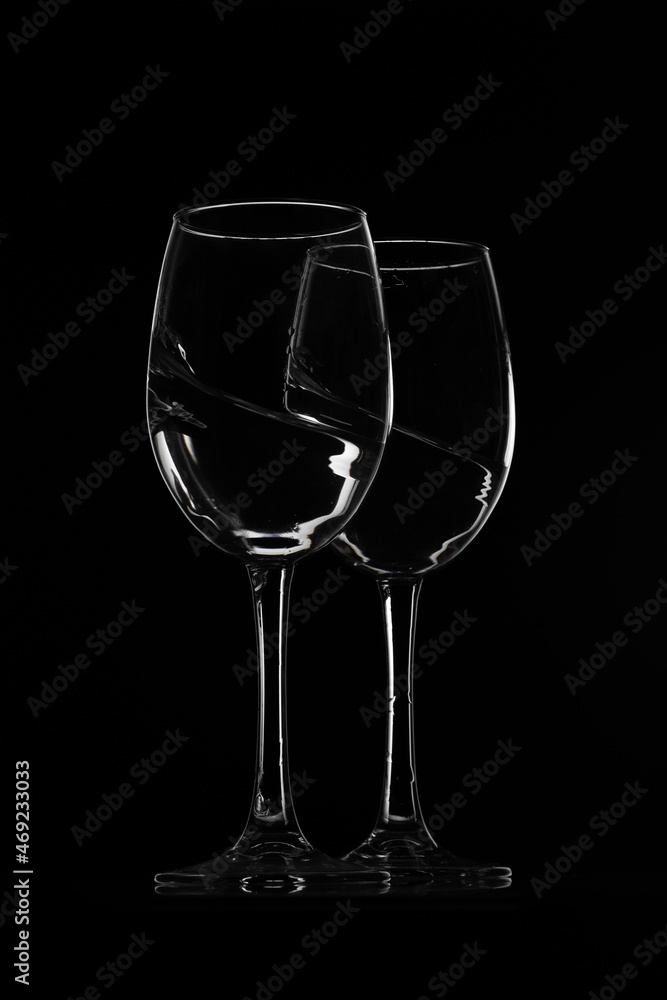 2 glasses of water with splashes on black background 2 glasses of water with splashes on black background