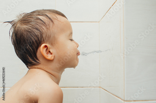 Tableau sur toile A child sitting in the bathroom spits water on the wall