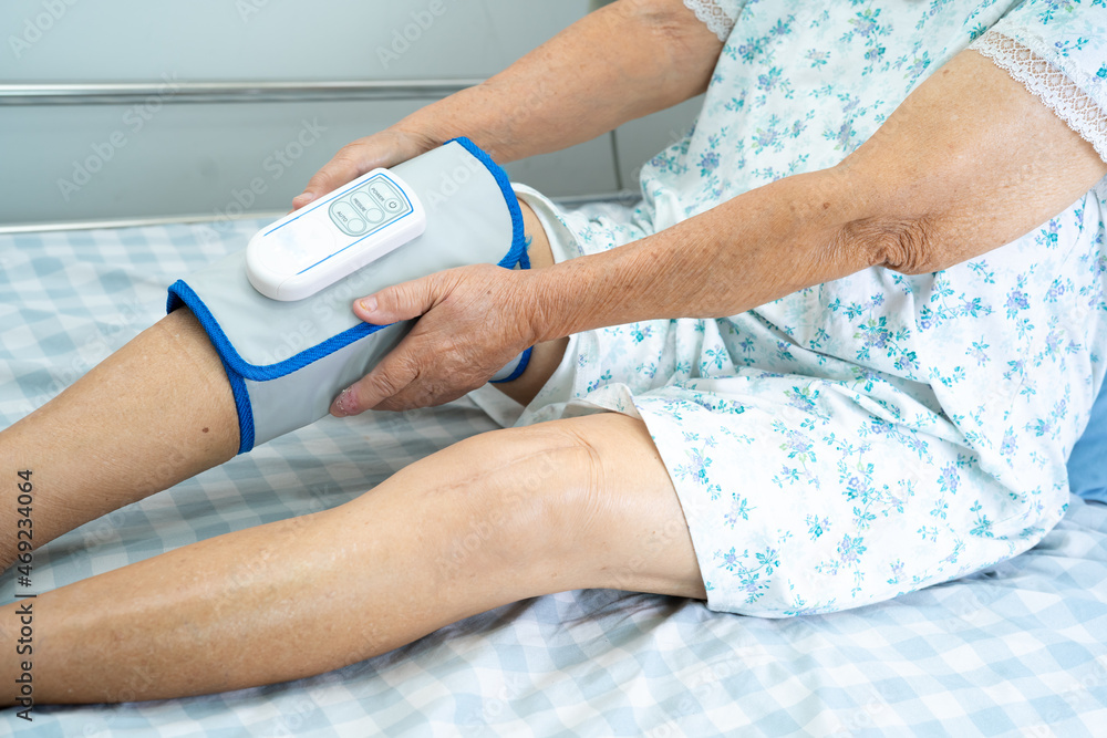 Asian senior or elderly old woman patient with Cordless Air Compression Pressure Leg Massage on the bed in nursing hospital.
