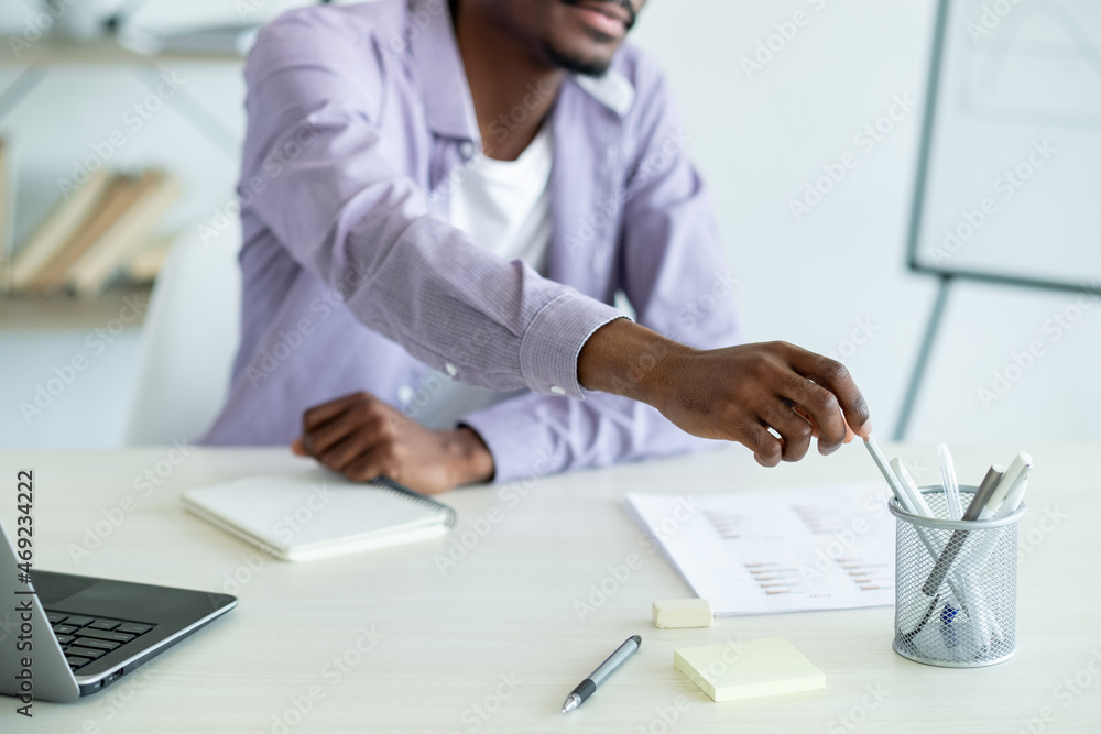 Educational courses. Working man. Make notes. Casual unrecognizable guy choosing pen for writing in copybook in light room interior. Educational courses. Working man. Make notes. Casual unrecognizable guy choosing pen for writing in copybook in light room interior.