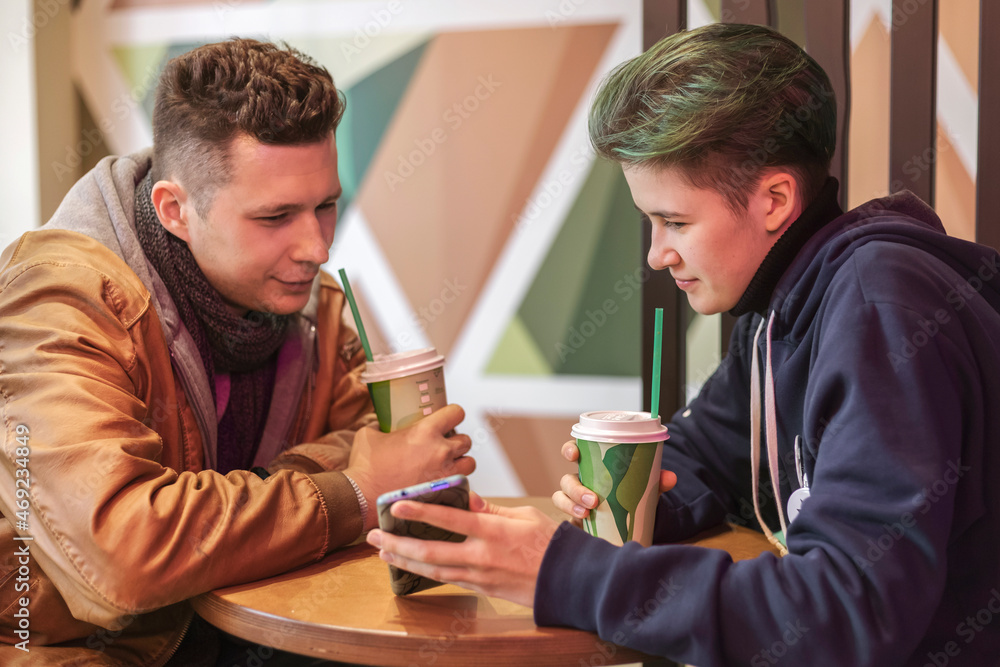 A guy and a girl are sitting in a cafe and using smartphones. Communication, technology, internet. A guy and a girl are sitting in a cafe and using smartphones. Communication, technology, internet.