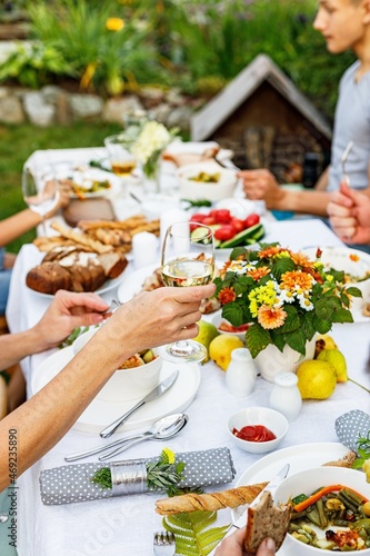 A festive family dinner or barbecue in the summer garden. Family leisure and celebration and food concept. People are eating at a garden party. BBQ, vegetables, wine and snacks. Life in the suburbs