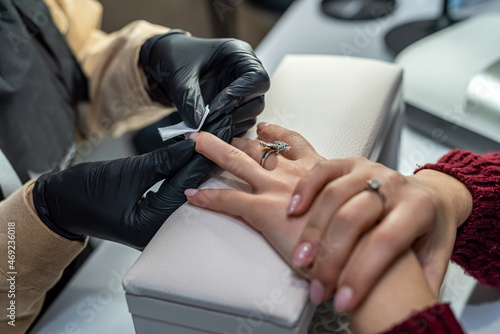 in salon nail specialist makes a gel varnish coating for a regular client during a pandemic.
