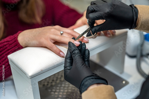 in salon nail specialist makes a gel varnish coating for a regular client during a pandemic.