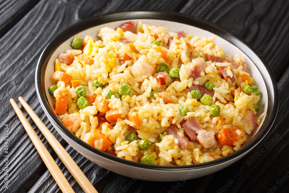Yangzhou stir fried rice with egg and vegetables such as carrots, peas as well as shrimps, meat close up in the plate on the table. Horizontal Yangzhou stir fried rice with egg and vegetables such as carrots, peas as well as shrimps, meat close up in the plate on the table. Horizontal