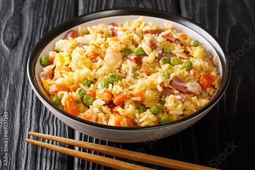 Traditional fried Chinese rice with vegetables, eggs, shrimps, pork close-up in a bowl on the table. horizontal
