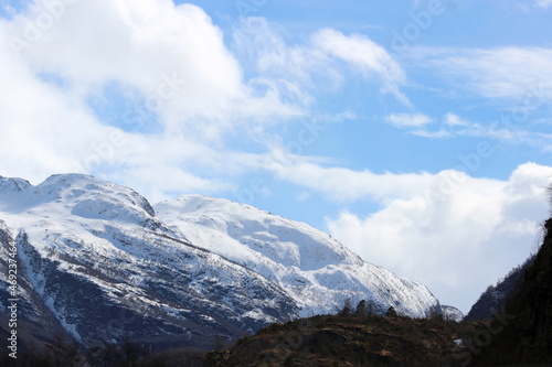 Snow covered mountains in bright frosty and sunny day with blue sky and white butterflies