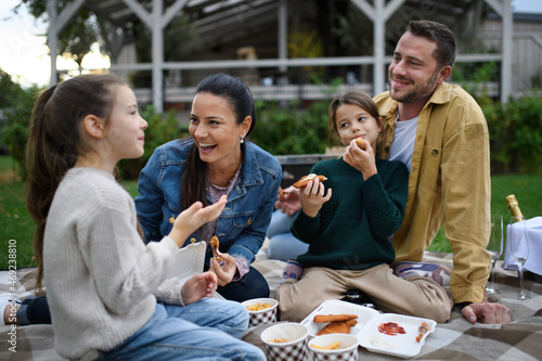 Happy young family sitting on blanket and having take away picnic outdoors in restaurant area.