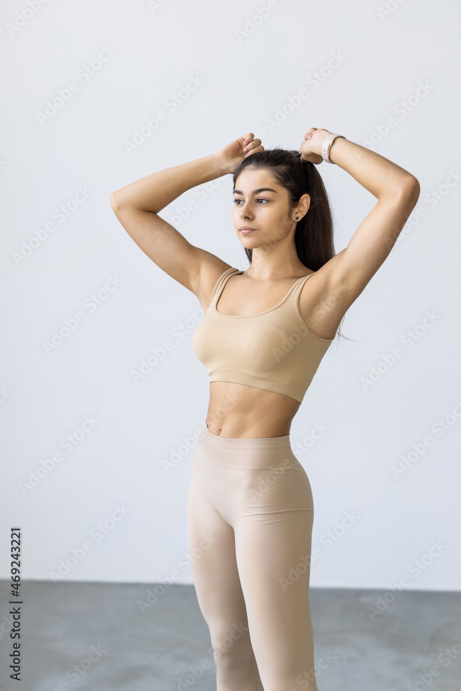 Fototapeta premium Sporty slim woman with ponytail fitness woman enjoys workout exercise on white background