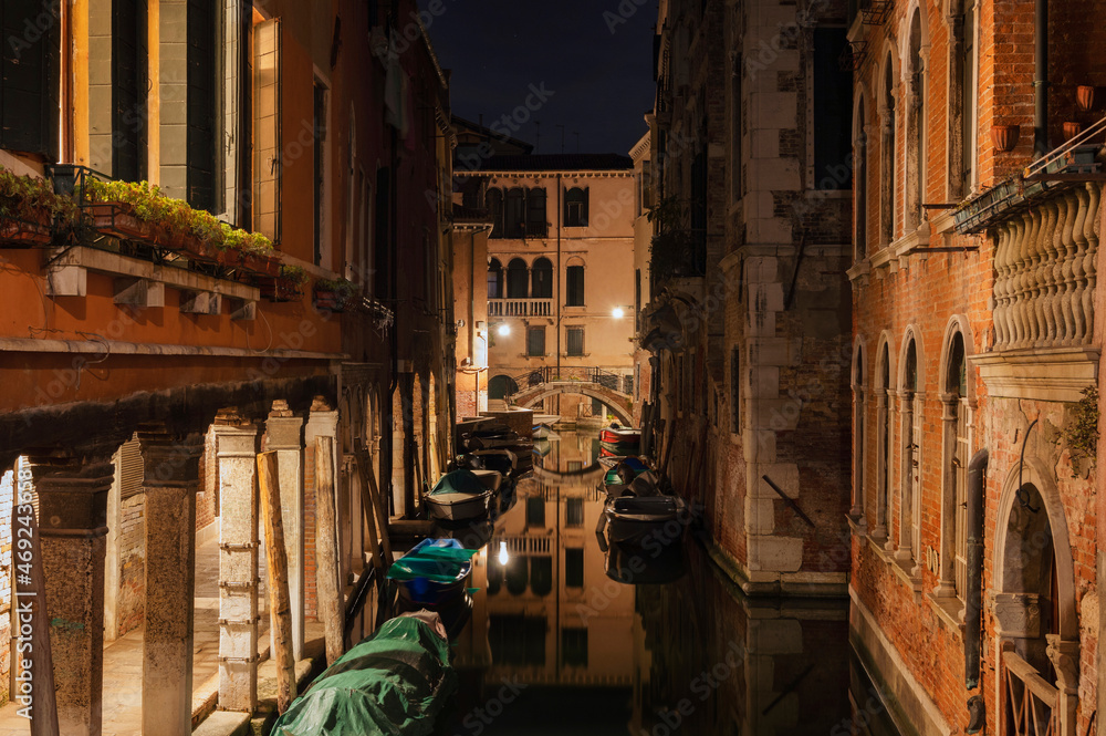 Canal with boats during night in Venice, Italy. (long exposure photo)