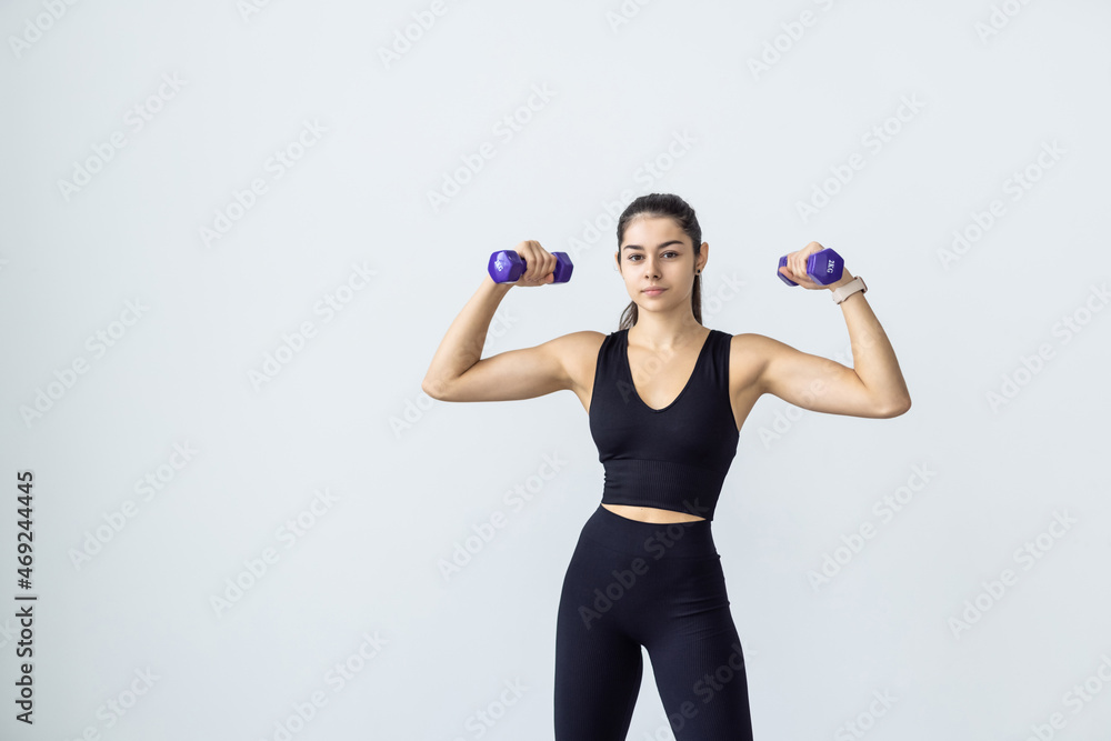 Young smiling young woman with dumbbells exercising at home Young smiling young woman with dumbbells exercising at home