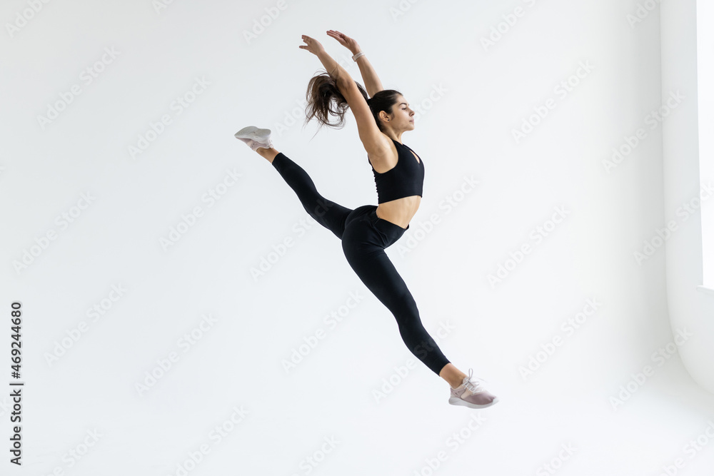 Side view of a sporty young woman jumping on white background
