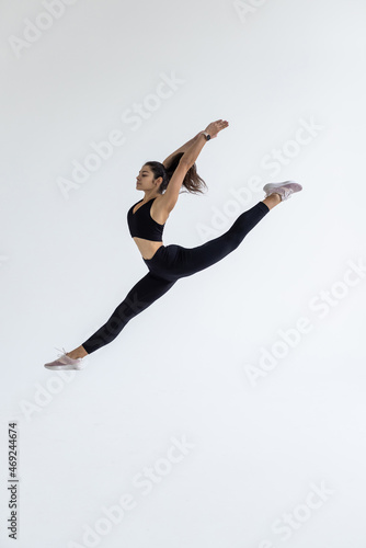 The portrait of beautiful young brunette woman gymnast training calilisthenics exercise with acrobatic element on white studio background. Art gymnastics concept.