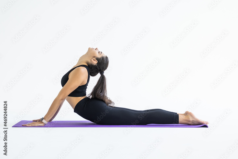 Beautiful fit yogini woman practices yoga asana bhujangasana cobra pose isolated on white background