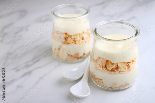 Napoleon cake with cream in small vintage jars on marble background.