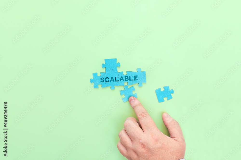 Businessman connecting puzzle pieces with the word Scalable Businessman connecting puzzle pieces with the word Scalable
