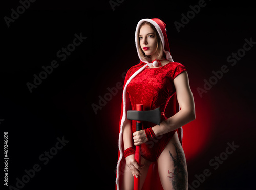 militant girl in a Christmas red Santa Claus cape with an axe in her hands