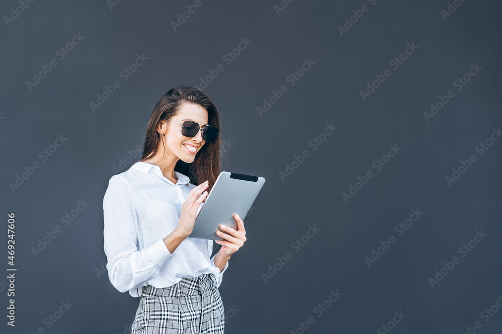 Young business woman with coffee and tablet on grey background. Young business woman with coffee and tablet on grey background.