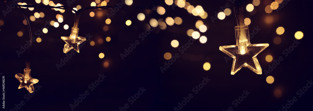 Obraz Christmas warm gold garland lights over dark background with glitter overlay fototapeta, plakat