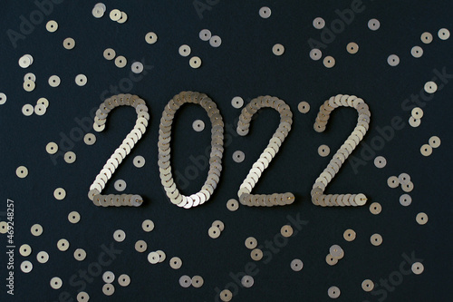 2022 embroidered with golden sequins on black textured background with scattered random sequins as Happy New Year decoration