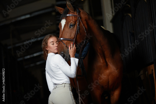 Portrait of smiling female jockey standing by horse in stable