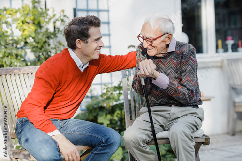 Happy man talking to elderly father in backyard photo
