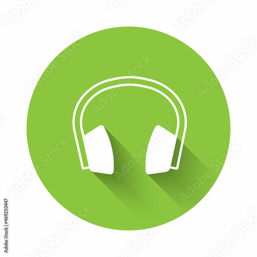 White Noise canceling headphones icon isolated with long shadow background. Headphones for ear protection from noise. Green circle button. Vector