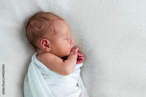 Sweet newborn baby sleeping in white bed. Lifestyle portrait