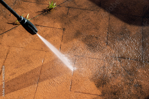 Cleaning dirty backyard paving tiles with pressure washer cleaner. photo