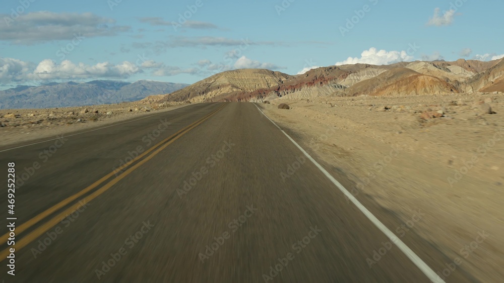 Road trip to Death Valley, Artists Palette drive, California USA. Hitchhiking auto traveling in America. Highway, colorful bare mountains and arid climate wilderness. View from car. Journey to Nevada.