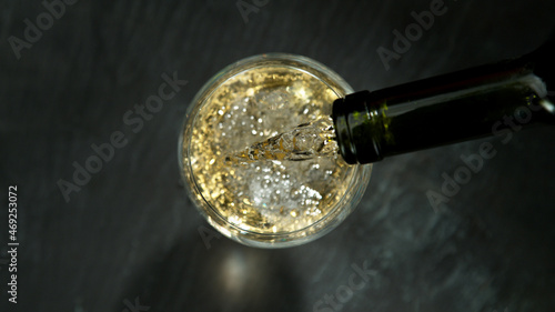 Pouring white wine, black stone background. Top view.