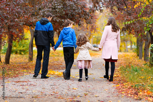 family walks in the autumn park along the path. they are surrounded by beautiful nature and trees with yellow and red leaves