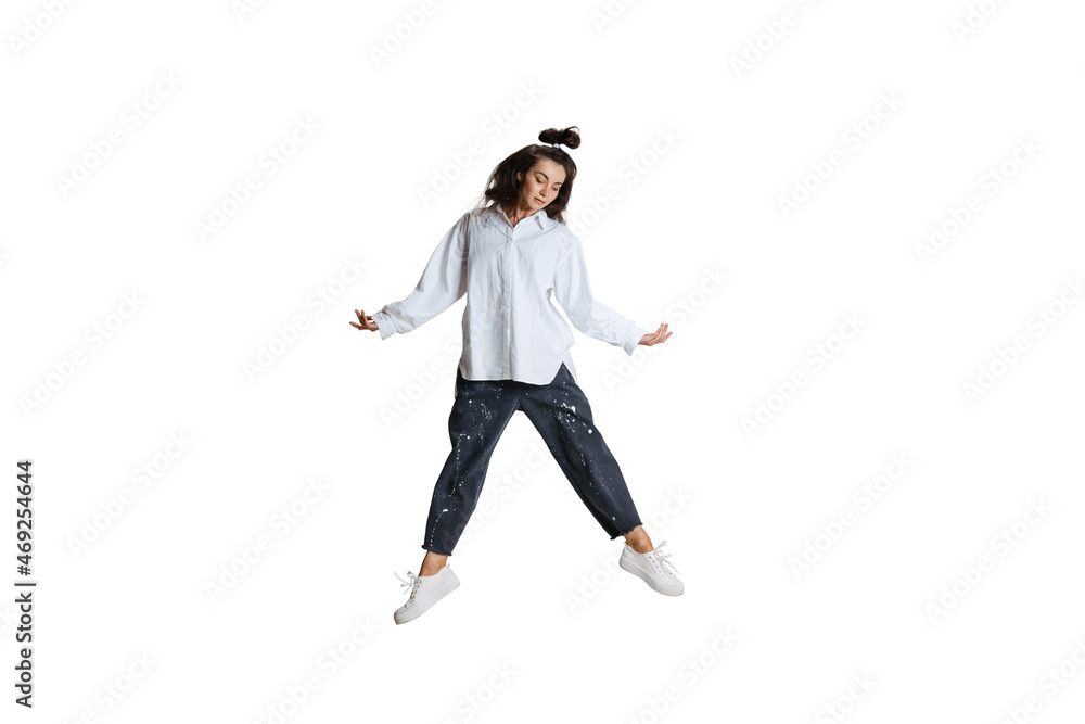 Studio shot of young woman in casual wear jumping, flying isolated on white background. Art, motion, action, flexibility, inspiration concept. Studio shot of young woman in casual wear jumping, flying isolated on white background. Art, motion, action, flexibility, inspiration concept.
