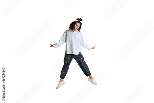 Studio shot of young woman in casual wear jumping, flying isolated on white background. Art, motion, action, flexibility, inspiration concept.