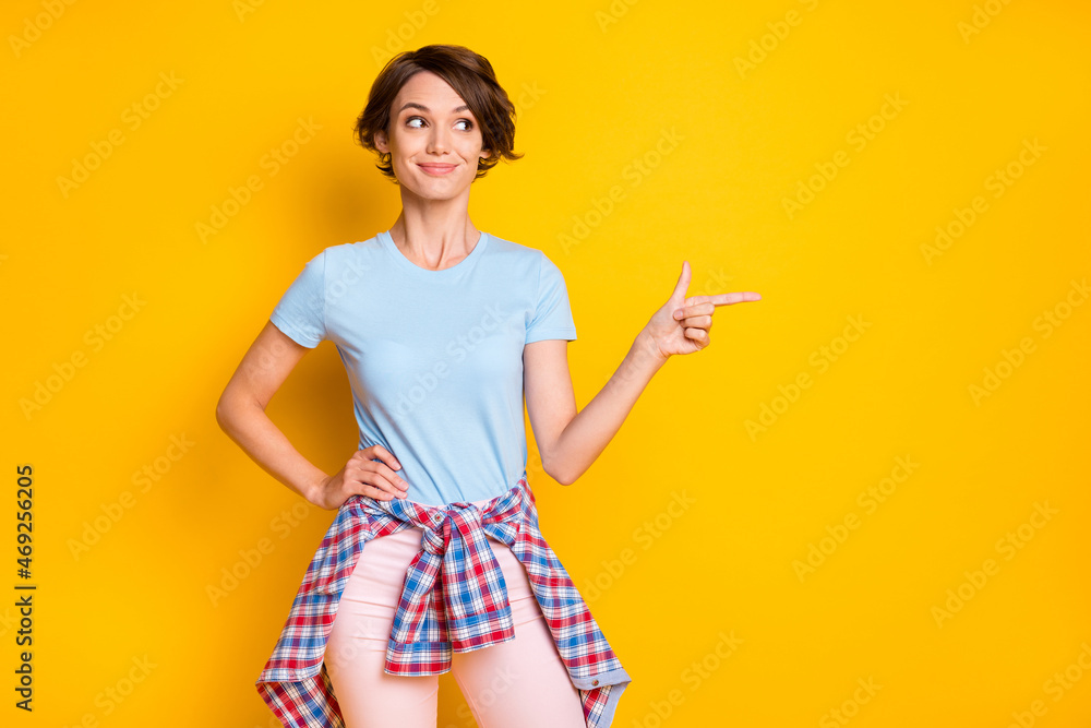 Photo portrait of woman looking pointing finger at blank space with shirt on waist isolated on vivid yellow colored background