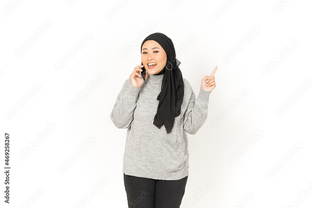 Using smartphone and pointing aside of Beautiful Asian Woman Wearing Hijab Isolated On White Using smartphone and pointing aside of Beautiful Asian Woman Wearing Hijab Isolated On White