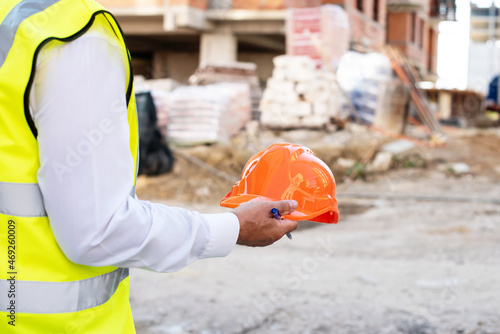 Orange hard safety helmet hat. Construction or engineering concept. Foreman officer inspector, Engineer or inspector at construction site checking and inspecting progressing work in construction site
