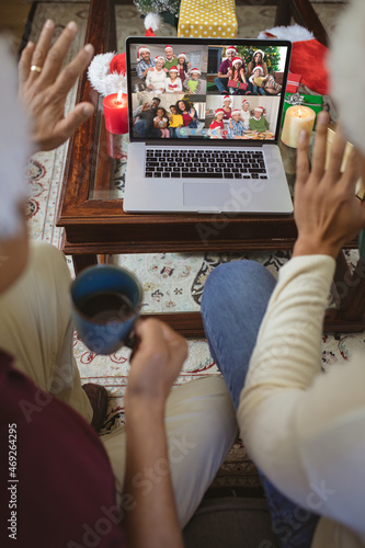 Two waving men making laptop christmas group video call with four diverse happy families