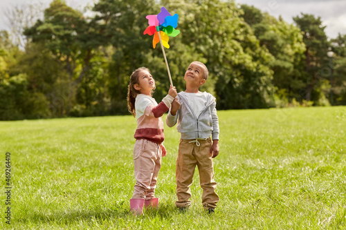 childhood, leisure and people concept - happy kids with pinwheel having fun at park
