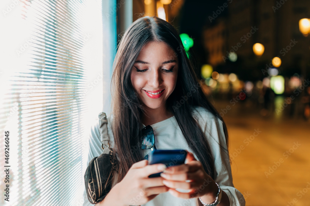 Woman using smart phone leaning on glass wall Woman using smart phone leaning on glass wall