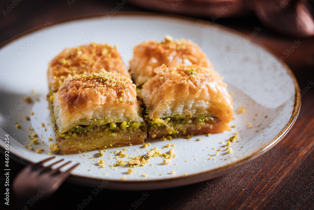 Turkish or Bosnian dessert called Baklava with pistachio served with traditional Turkish or Bosnian coffee set on a wooden board in moody atmosphere
