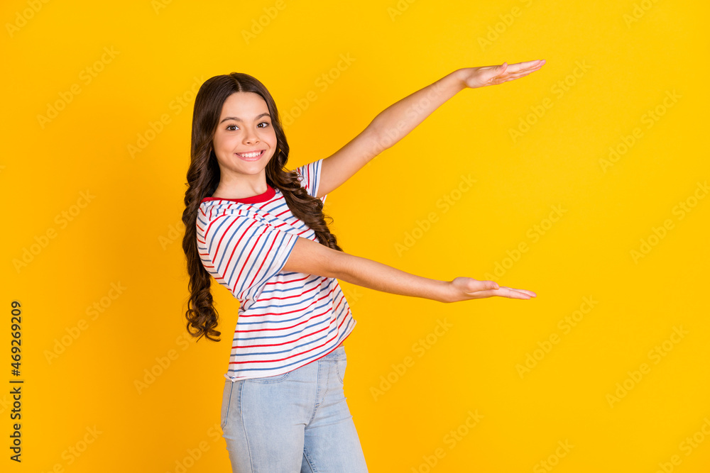 Profile side photo of young preteen girl happy smile show hands big huge size isolated over yellow color background Profile side photo of young preteen girl happy smile show hands big huge size isolated over yellow color background