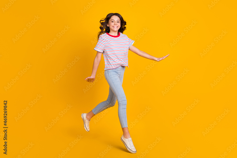 Full size profile side photo of young schoolgirl happy positive smile go walk step jump isolated over yellow color background