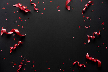 close up on group of red color of rolling ribbon and confetti on black background with copy space for merry christmas, happy new year festival and black friday sale season concept