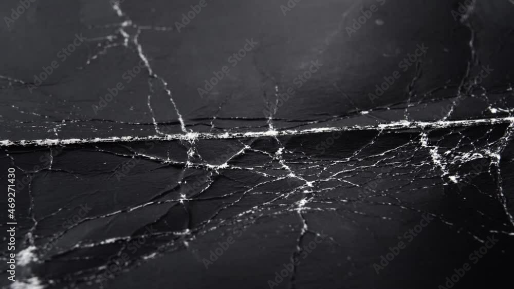Worn black cardboard with wrinkles and cracks. Paper dark abstract background for design. Old packaging material. The concept of Halloween and horror movies. Macro. Slow rotation