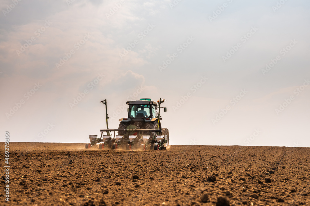 Fototapeta premium Tractor drilling seeding crops at farm field. Agricultural activity.
