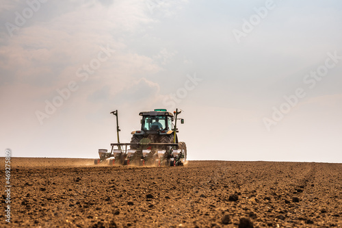 Tractor drilling seeding crops at farm field. Agricultural activity. photo