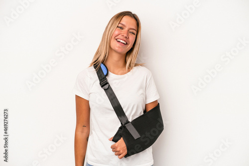 Young caucasian woman with broken hand isolated on white background laughing and having fun.