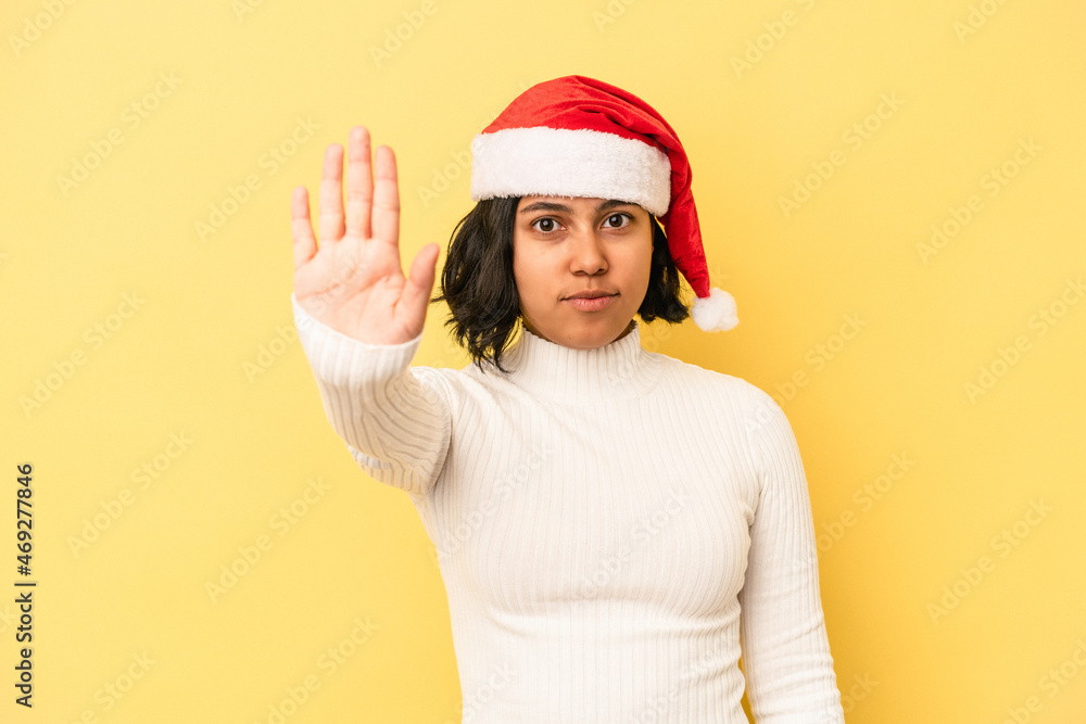 Young latin woman celebrating christmas isolated on yellow background standing with outstretched hand showing stop sign, preventing you. Young latin woman celebrating christmas isolated on yellow background standing with outstretched hand showing stop sign, preventing you.