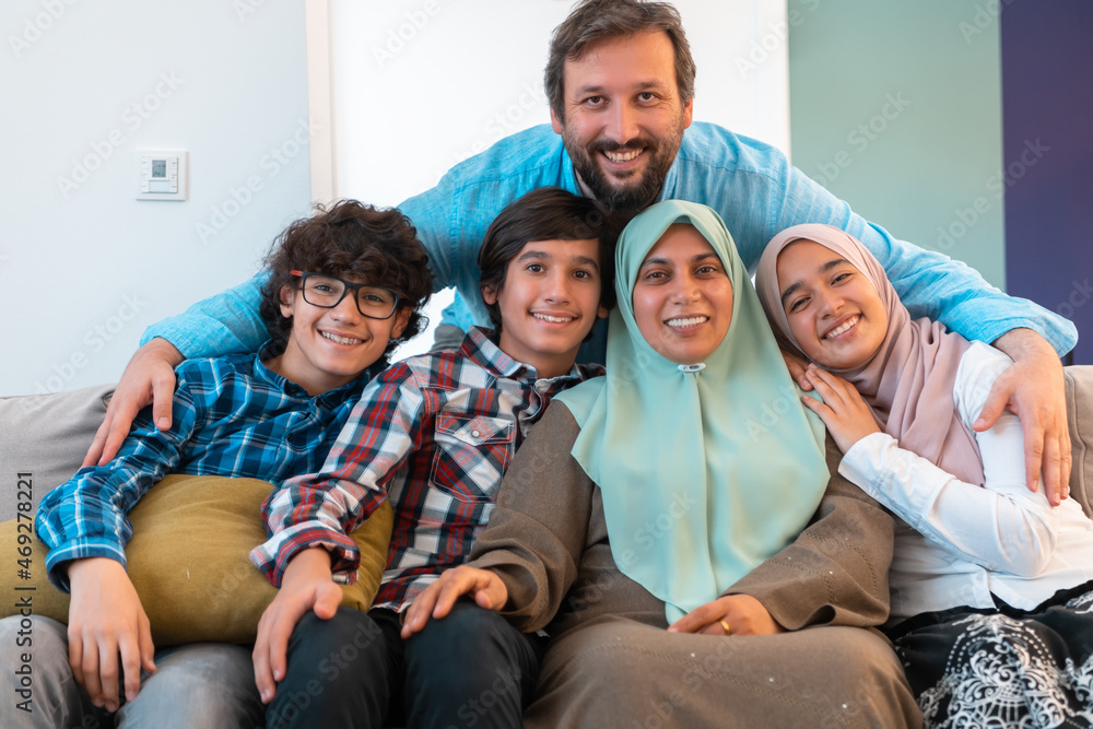 Portrait photo of an arab muslim family sitting on a couch in the living room of a large modern house. Selective focus Portrait photo of an arab muslim family sitting on a couch in the living room of a large modern house. Selective focus